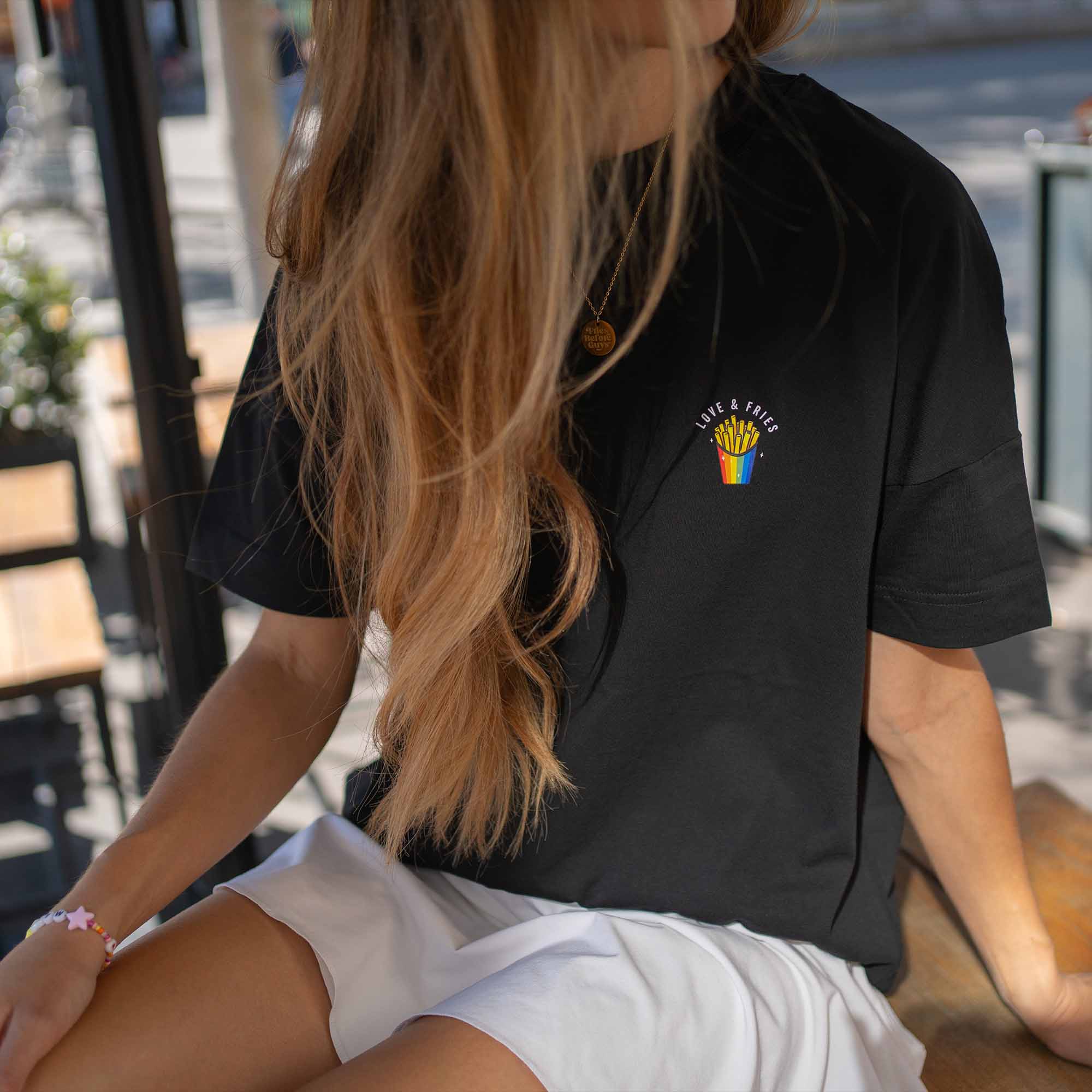 Sitzendes Mädchen in schwarzem T-Shirt mit "Love & Fries" Print