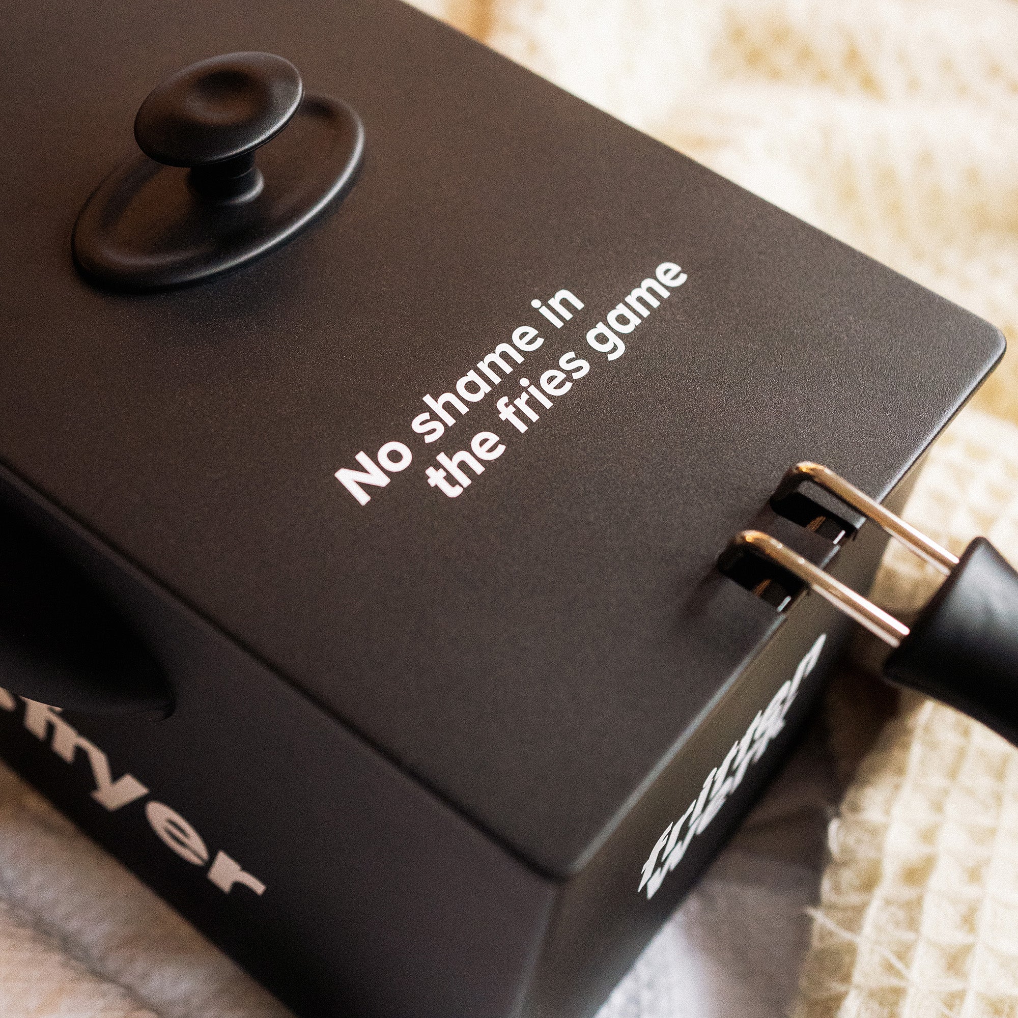 Nahaufnahme von weißem "No shame in the fries game"-Druck auf schwarzer Fritteuse