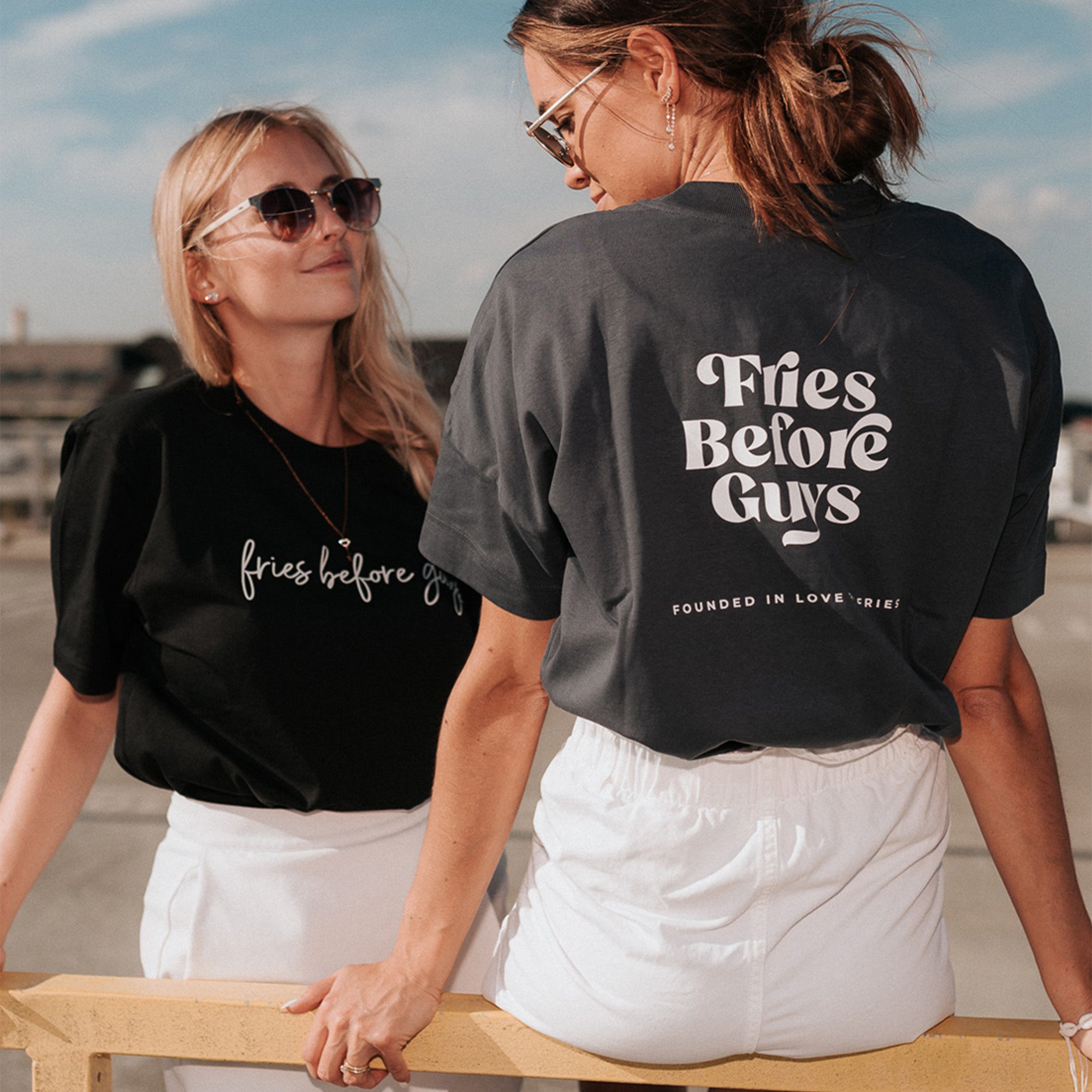 Frau trägt granitfarbenes T-Shirt mit weißem "Fries Before Guys"-Rückenprint.