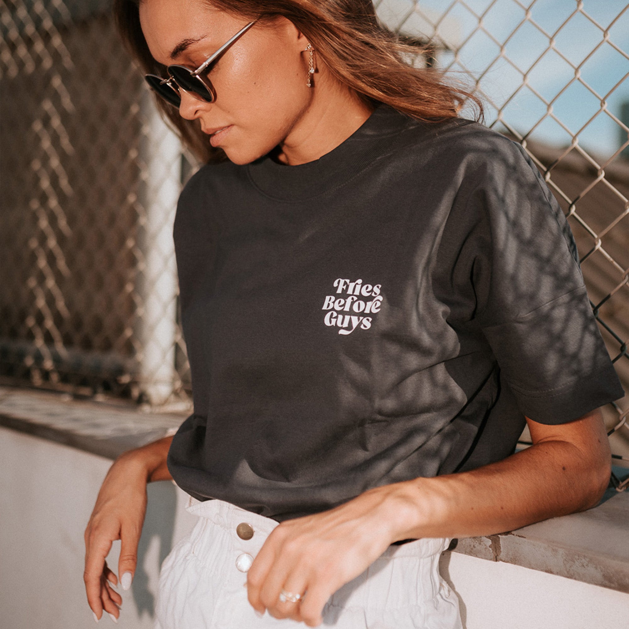 Frau trägt granitfarbenes T-Shirt mit kleinem weißem "Fries Before Guys"-Print auf der Brust.