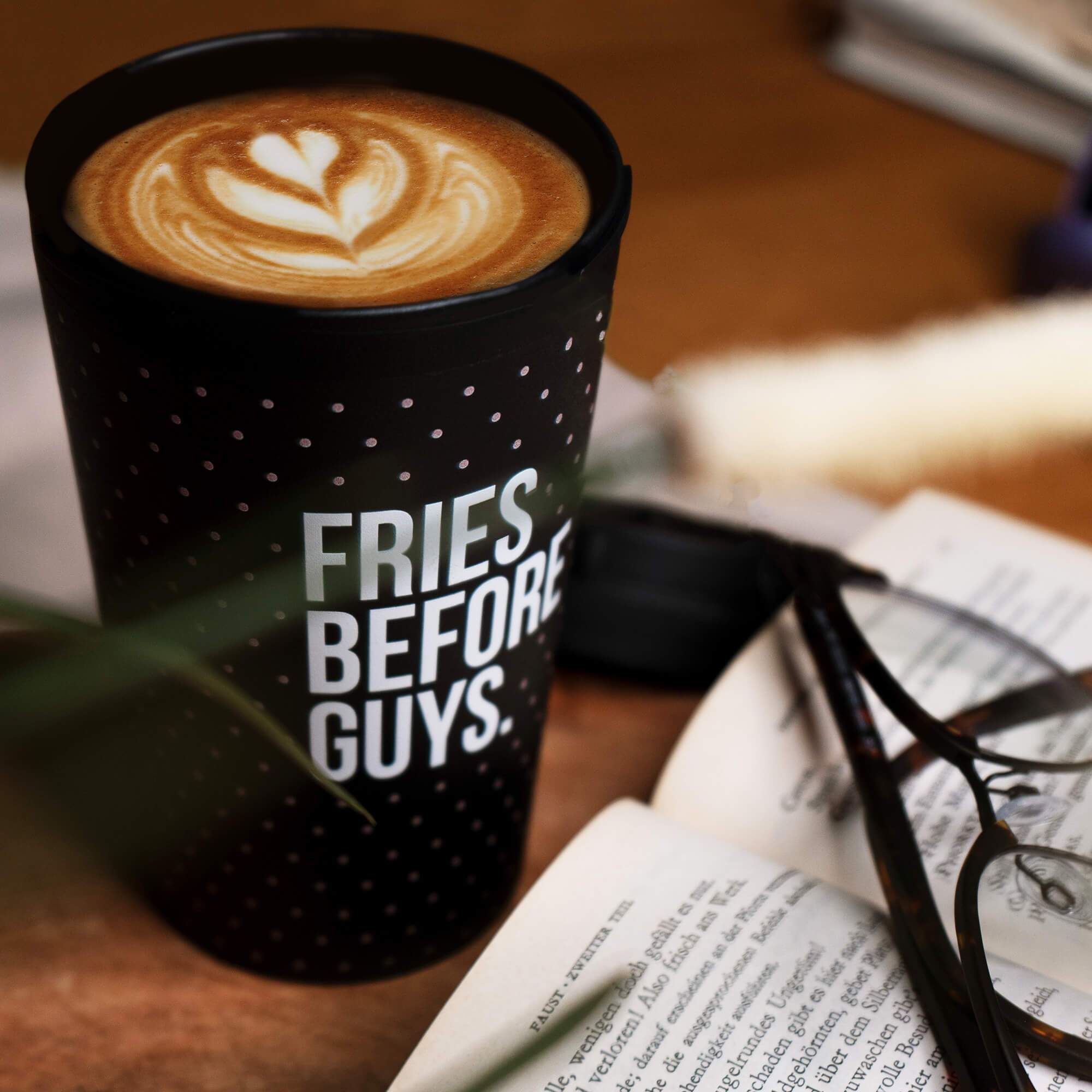 Gefüllter schwarzer Kaffeebecher mit Punkten und "Fries Before Guys"-Print