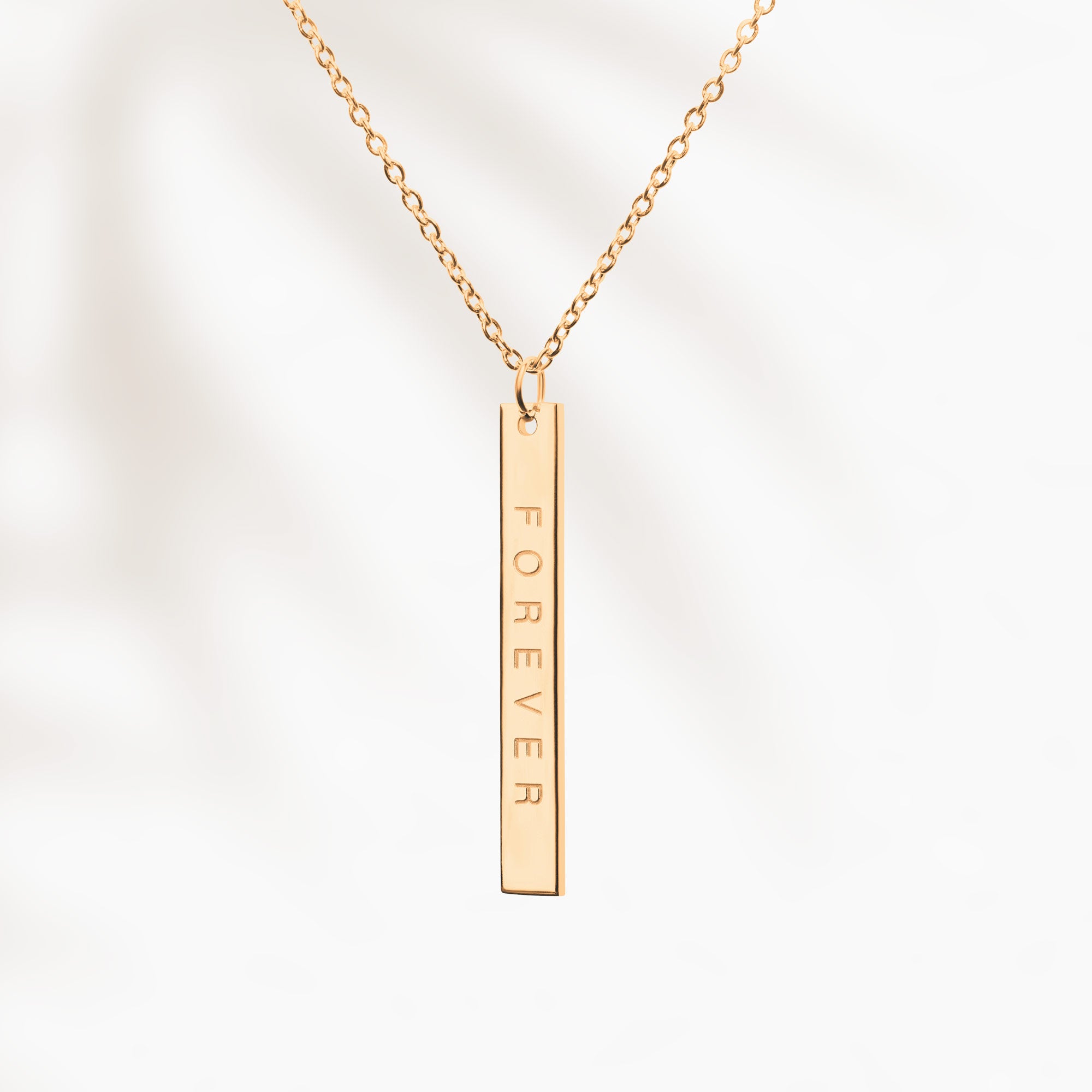 Goldene Kette mit länglichem Anhänger und "Forever"-Gravur auf der Rückseite.