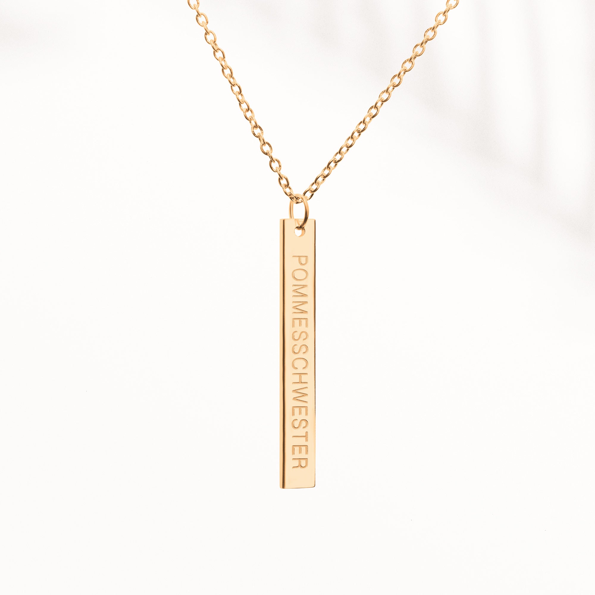 Goldene Kette mit länglichem Anhänger mit "Pommesschwester"-Gravur auf der Vorderseite.