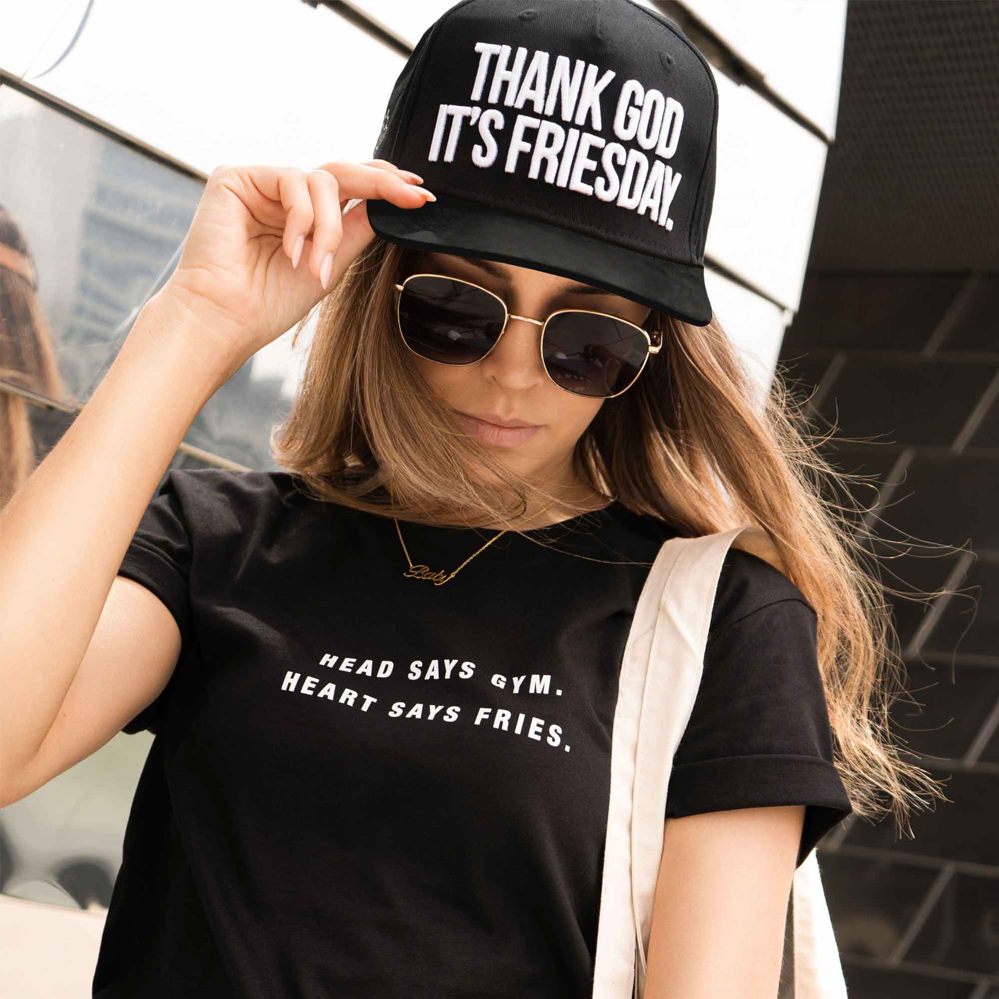 Frau trägt schwarze Snapback mit weißer "Thank God it's Friesday"-Stickerei
