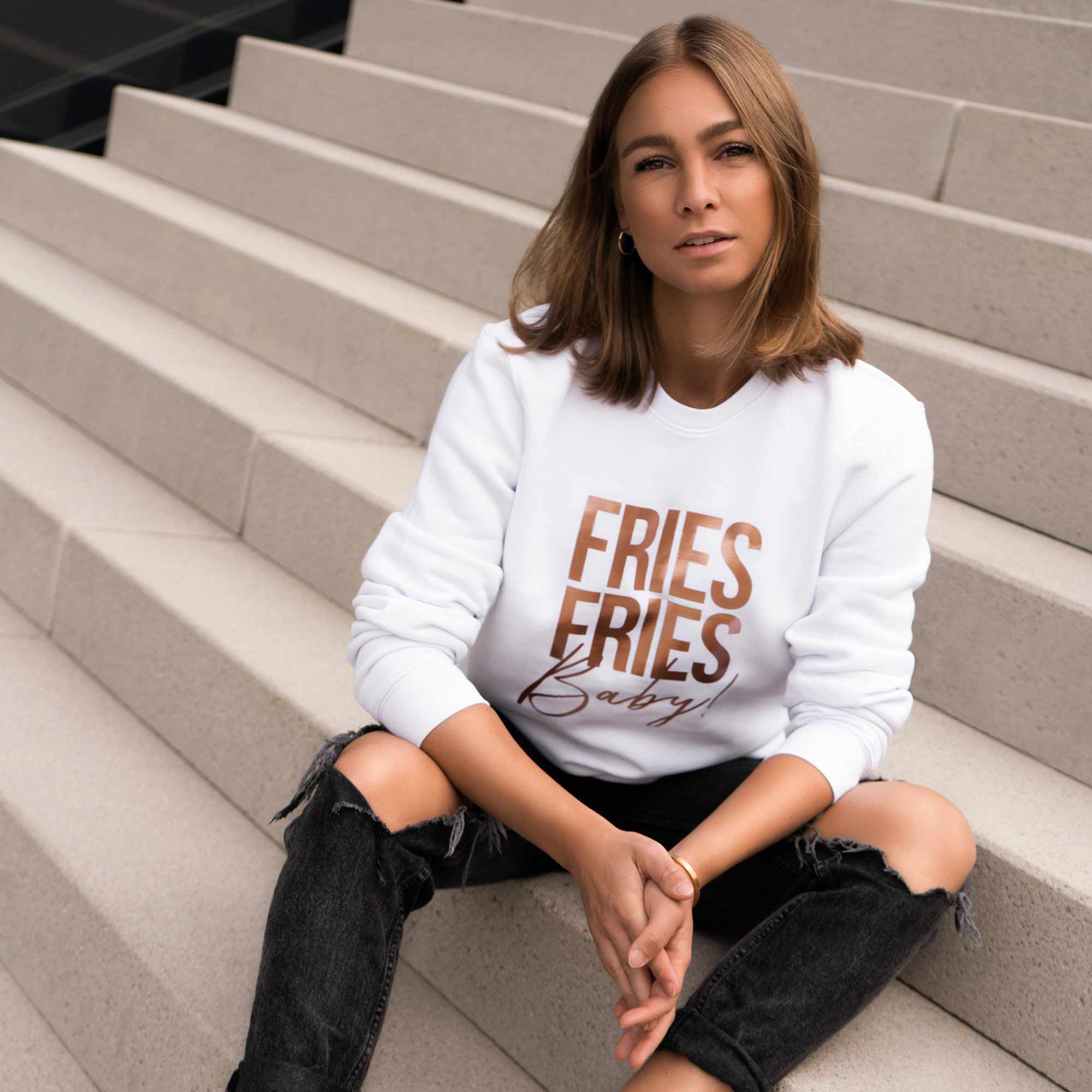 Frau trägt weißen Pullover mit metallic "Fries Fries Baby!"-Druck