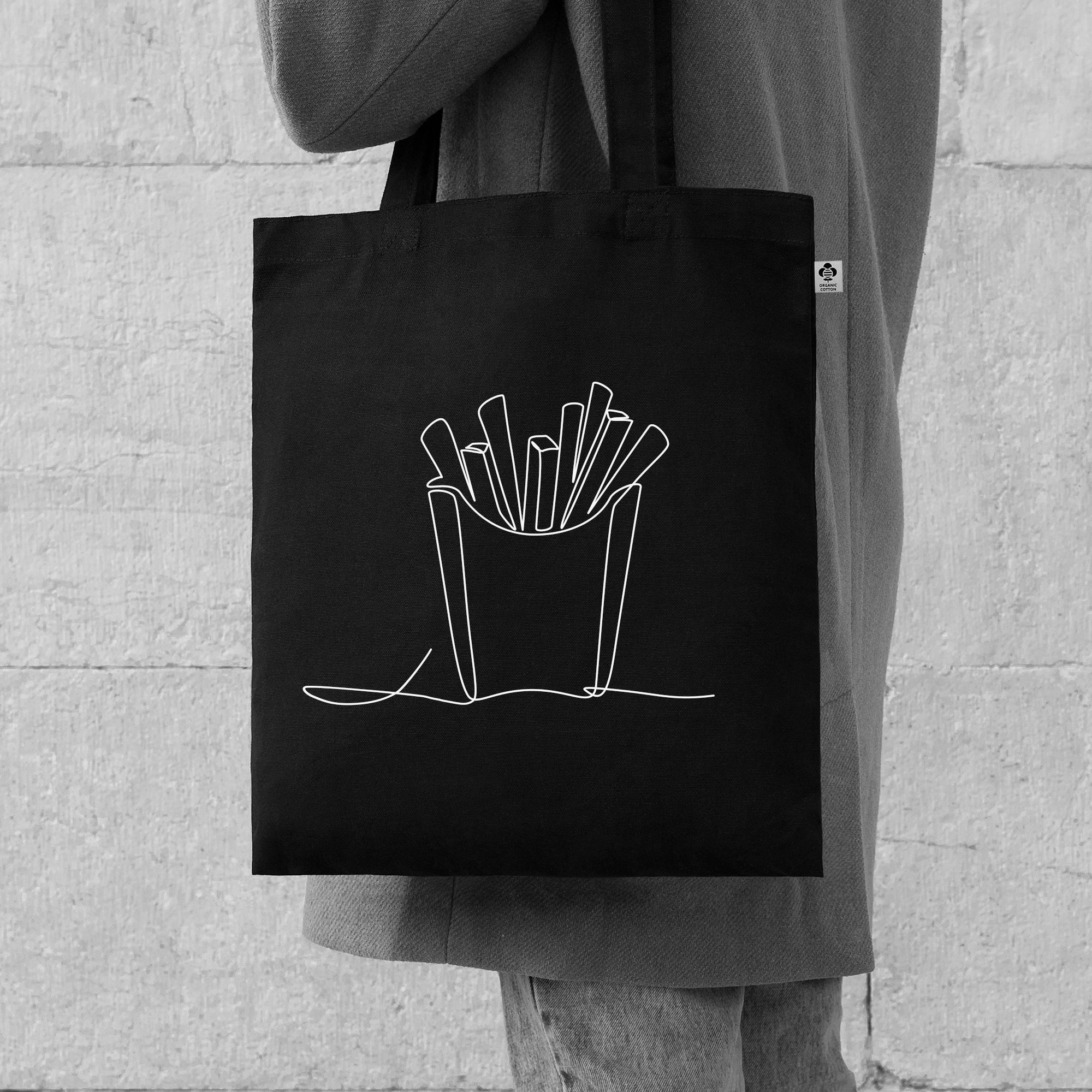 Person in grauem Outfit trägt schwarze Tragetasche mit weißem gezeichneten Motiv einer Pommestüte