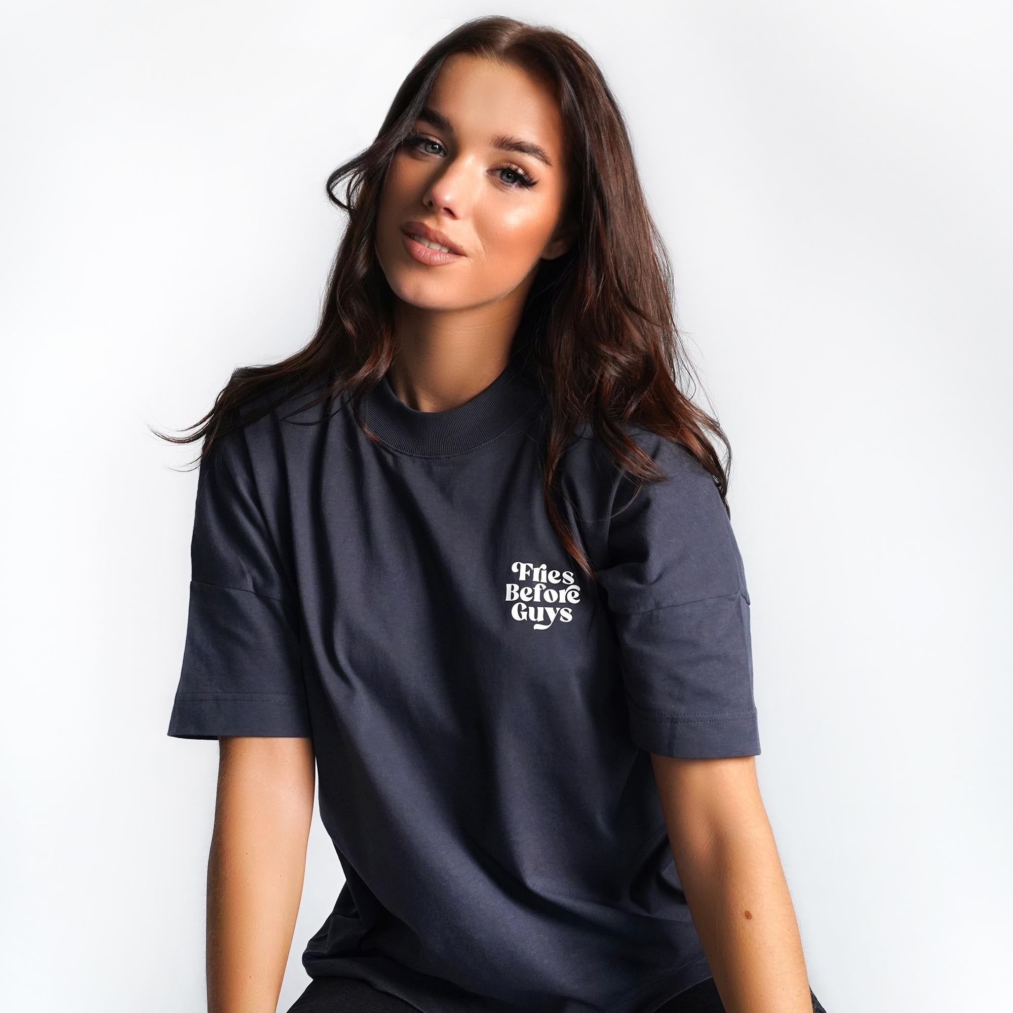 Braunhaarige Frau trägt granitfarbenes T-Shirt mit kleinem weißen "Fries Before Guys"-Druck.