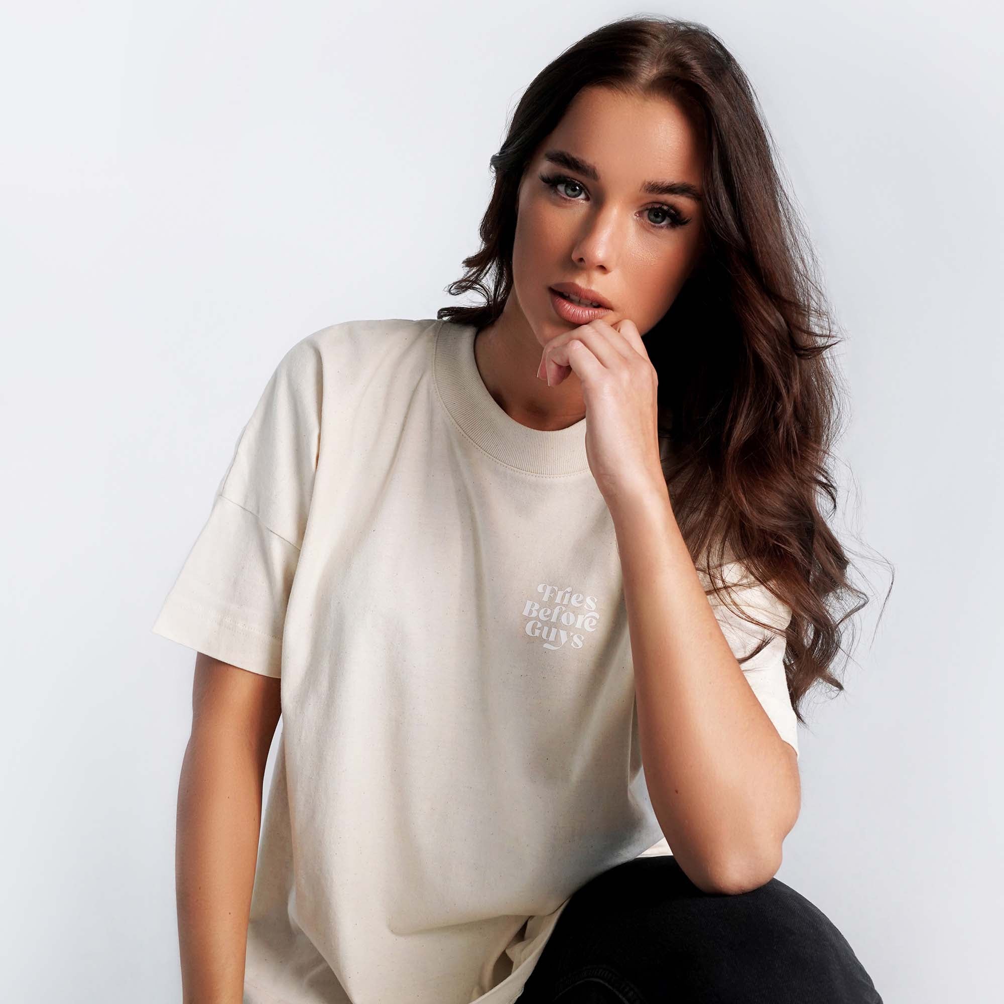 Frau trägt vanillafarbenes T-Shirt mit weißem "Fries Before Guys"-Druck