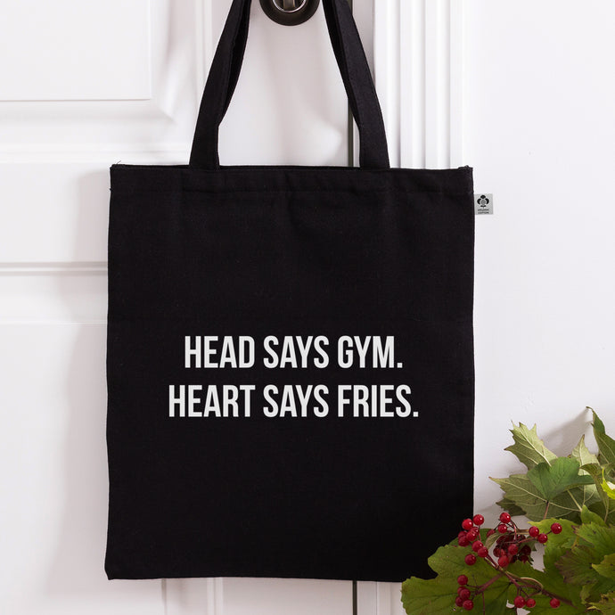 Schwarze Tragetasche mit weißem Head Says Gym. Heart Says Fries Druck